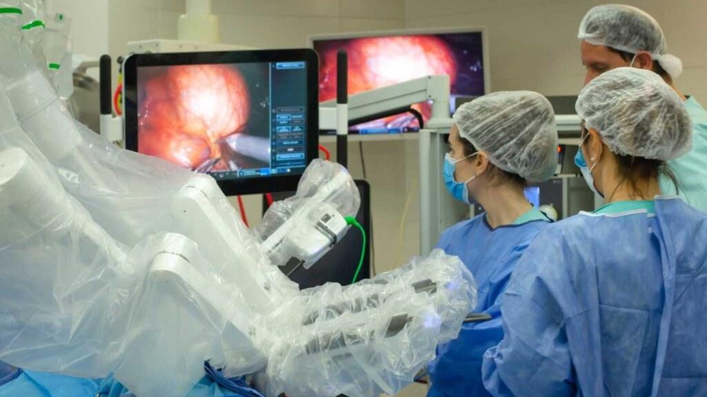 Equipo de UMIBA en quirófano con da Vinci en operación · pantalla auxiliar mostrando biomodelo MIRAI · navegación intraoperatoria touchless