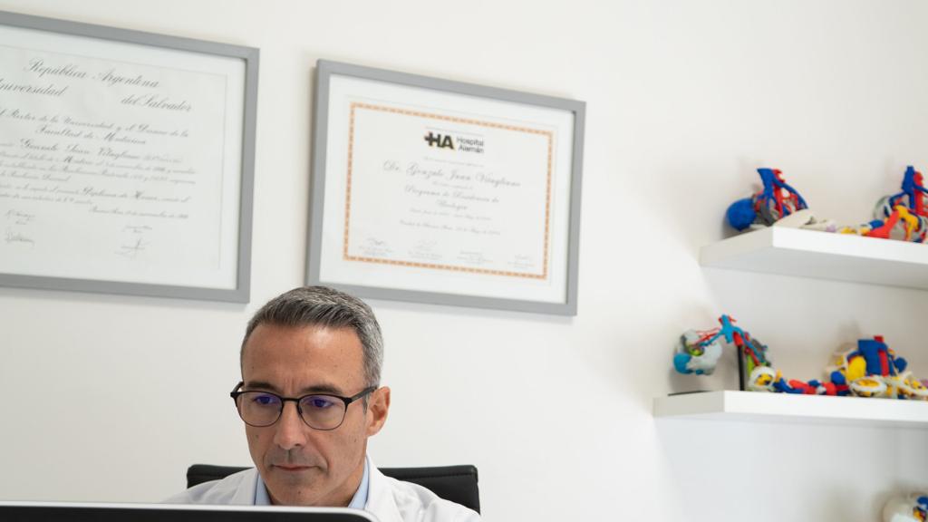 El Dr. Gonzalo J. Vitagliano trabaja frente a la computadora en su sala de consulta; detrás, sus diplomas.