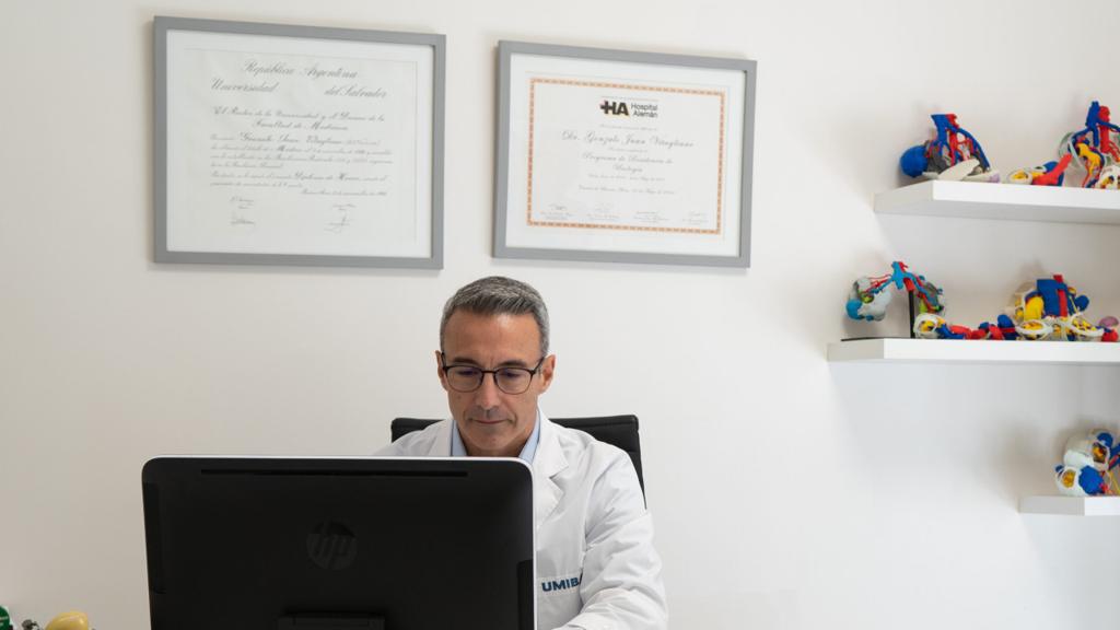 Sala de consulta de UMIBA en Recoleta: el Dr. Gonzalo J. Vitagliano trabaja en su escritorio; detrás, sus diplomas y estantes con modelos anatómicos 3D.
